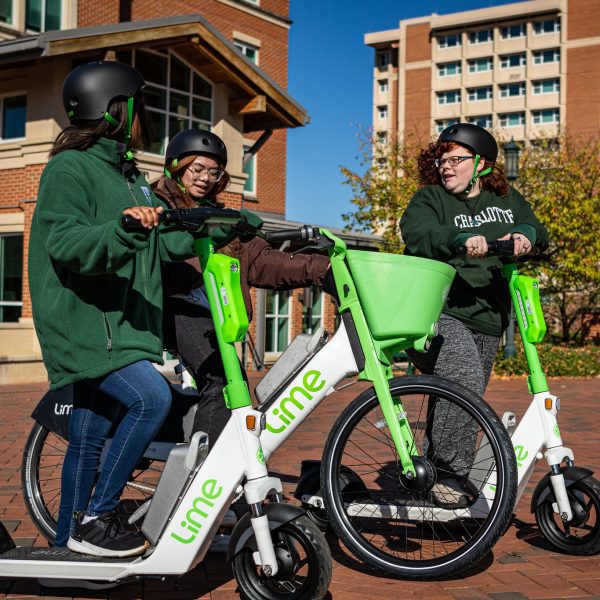 Three UNC Charlotte students riding Lime e-scooters and e-bikes.