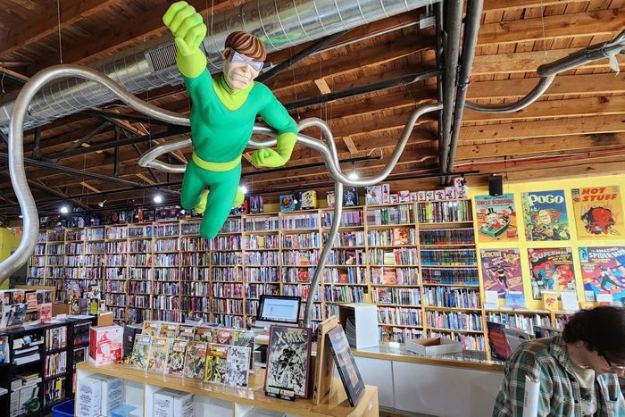 Dr. Octopus figure poses over shelves of comics in Heroes Aren't Hard to Find comic book shop