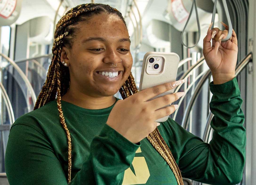 Student looking at phone while standing on bus