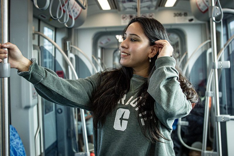 Female student tucking hair behind ear on light rail.