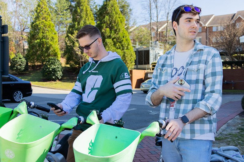 Students holding phones on Lime e-bikes.