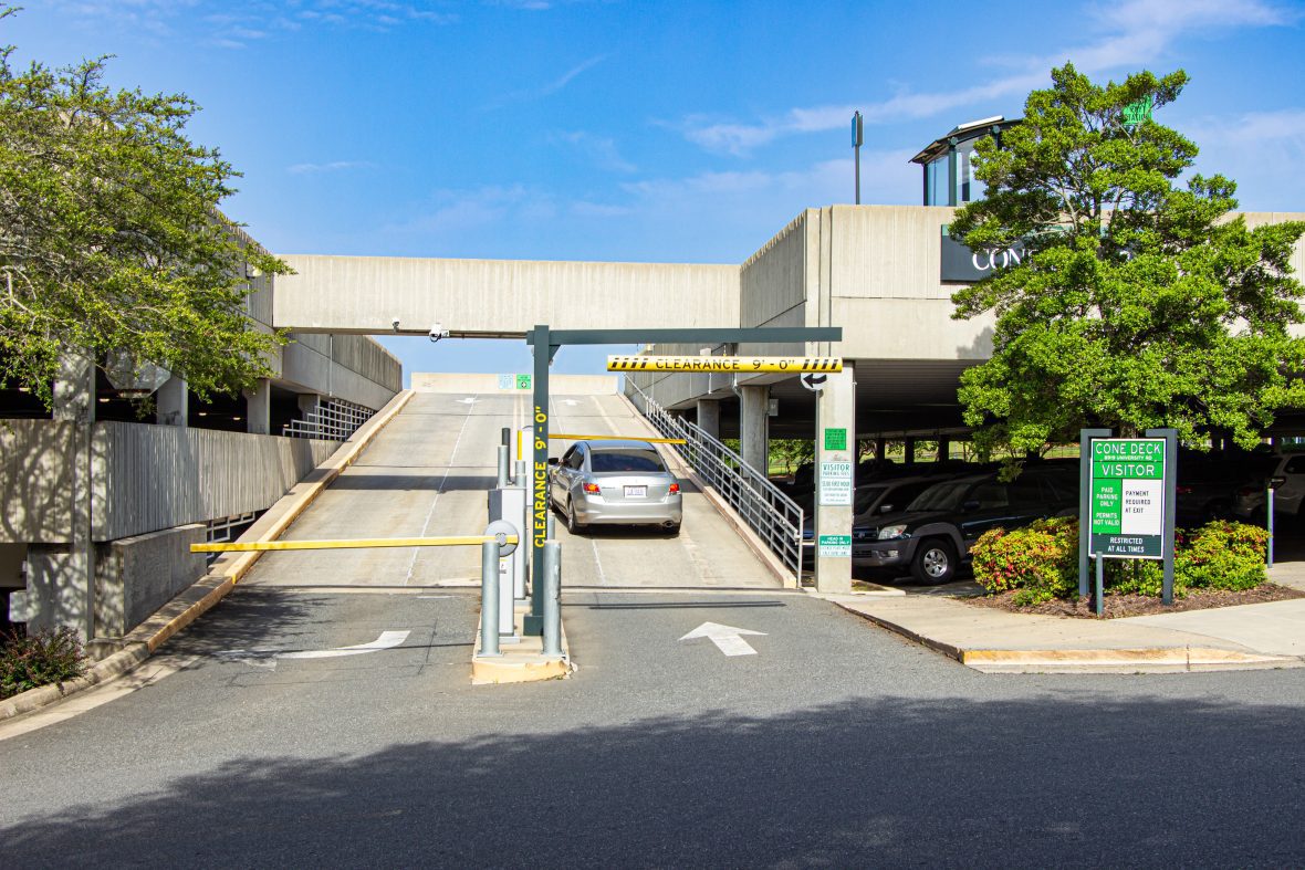 A car driving through entryway of a parking deck