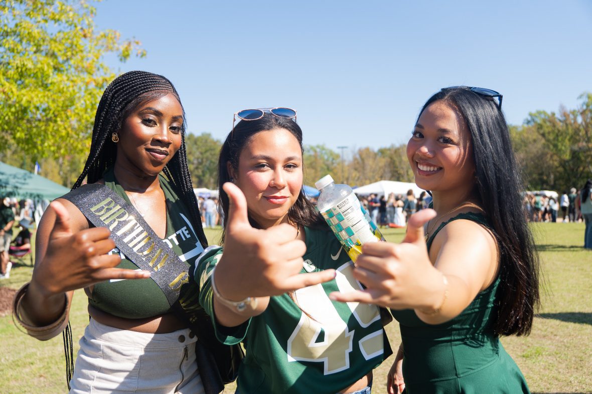 Three female students posing with thumbs and pinkies extended