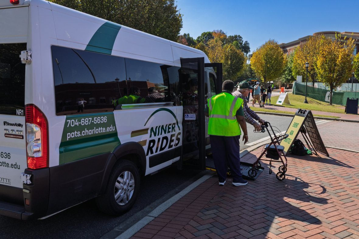 Man with walker exiting paratransit vehicle with assistant.