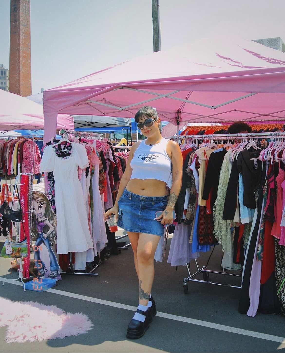 A girl at the vintage market, with a vendor of clothes behind her